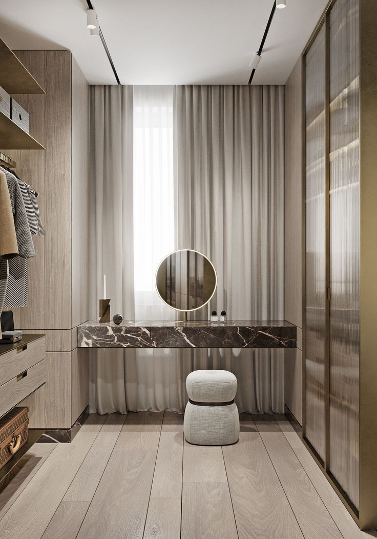 a modern dressing room with marble counter tops and wooden flooring, along with an oval mirror on the wall