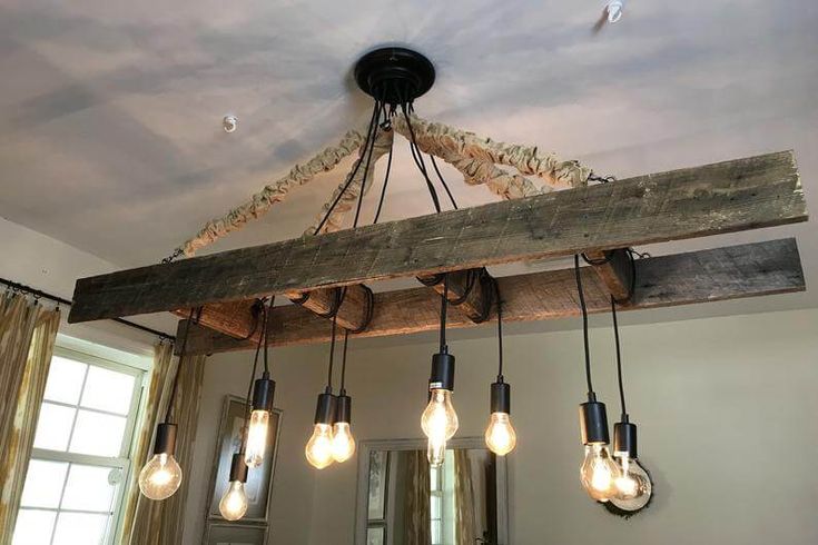 a light fixture hanging from the ceiling in a room with wood beams and lights on it