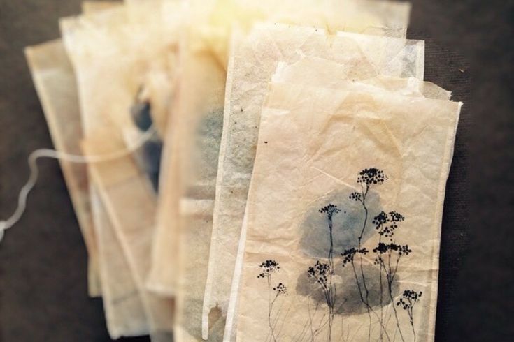 three pieces of paper with flowers on them sitting on a table next to some thread