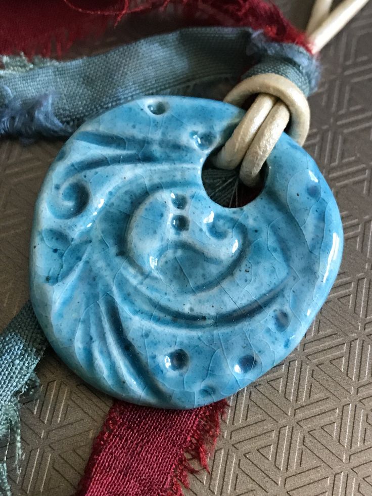 I spend a lot of time in the southwest and love to visit ancient ruins. I imagine the types of treasures that may have been found by the first visitors, and these inspire my creations. There is a distinct, rustic floral pattern on this pendant. This handmade clay pendant is created with Egyptian paste, which is created, dried very slowly, and fired once. In the drying process, salts form on the bead, which later melt and become the glaze. Because of this drying process, only the front and sides Artisan Turquoise Blue Necklace, Artisan Blue Turquoise Necklace, Artisan Blue Necklace With Artistic Design, Handmade Spiritual Turquoise Necklace With Round Pendant, One-of-a-kind Blue Turquoise Spiritual Necklace, Turquoise Handmade Amulet Necklace, Artisan Turquoise Necklace With Round Pendant, Handmade Blue Medallion Necklace, Spiritual Blue One-of-a-kind Turquoise Necklace