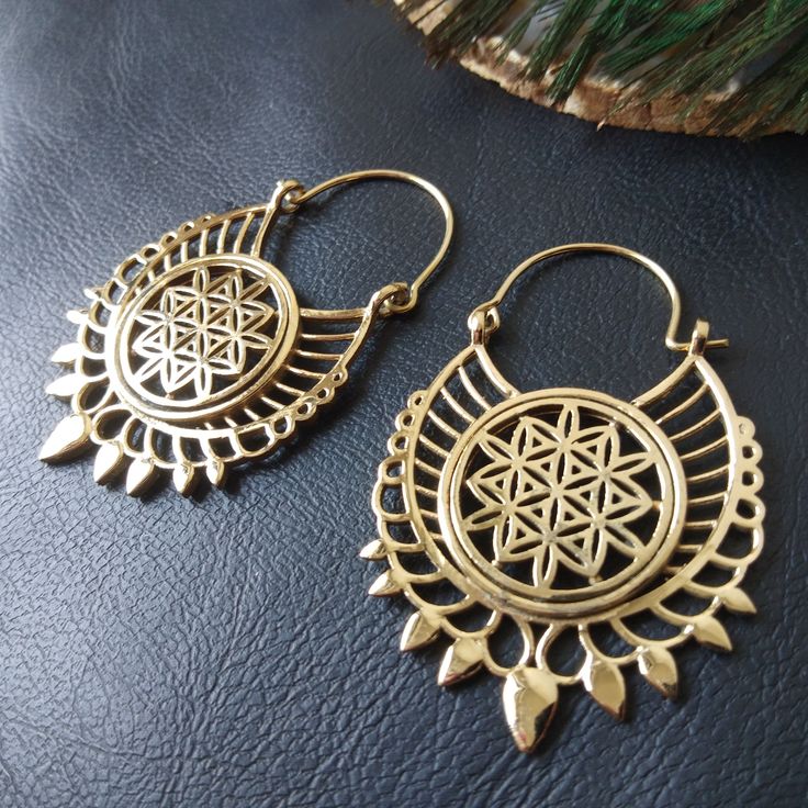 Openwork Hoop Earrings in Silver or Gold Brass. These Creoles are Elegantly Decorated with the Flower of Life Pattern Surrounded By A Circle. The Circle Of The Hoops Is Decorated With Spikes To Give These Earrings A More Ethnic Style. The Powerful Flower of Life Symbol Of Sacred Geometry Releases Good Waves. The Flower of Life Symbolizes Regeneration, Creation and Metamorphosis. She Represents the Cycle of Life. These Hoop Earrings are very elegant and they will illuminate your face. Timeless and Lightweight Creoles to Wear Everyday to Give an Ethnic Touch to Your Outfits. They are made from brass. Material: Brass Color: Silver or Gold Length: 5.7cm Width: 3.5cm Thickness: 0.2 cm Weight: 14 Gm The Pair Handmade Delivered in a Fabric Pouch Ideal for Gifting To offer or simply treat yourself Brass Hoop Earrings With Latkans For Festivals, Bohemian Small Hoop Plug Earrings, Bohemian Small Hoop Earrings For Festivals, Bohemian Round Hoop Earrings For Festivals, Brass Dangle Hoop Earrings With Latkans, Bohemian Handmade Small Hoop Cartilage Earrings, Bronze Pierced Hoop Earrings For Festivals, Adjustable Teardrop Hoop Earrings For Festival, Nickel-free Drop Hoop Earrings For Festivals