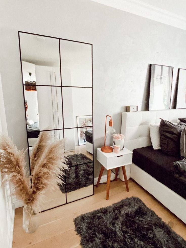 a living room with black and white furniture and mirrors on the wall, rugs in front of it