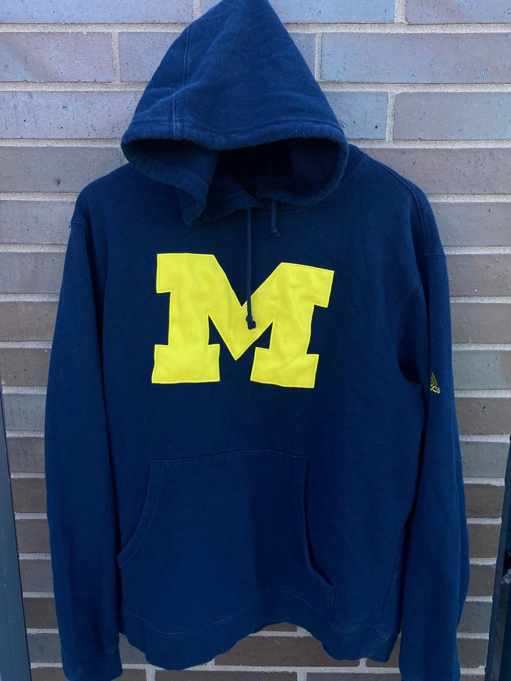 Vintage 1990s University of Michigan Wolverines Blue & Maize Adidas Pullover Hoodie Sweater - Length 26" Chest 21" - 60% Cotton 40% Polyester - Overall great vintage condition - Perfect for fall - Message for more information Please take note of the measurements listed as these are vintage clothes and may fit different than the tag size. Follow our page for more vintage clothing drops! Connect with us on Instagram: @recurarchives Collegiate Long Sleeve Hoodie With Logo Print, Throwback Hooded Top For College, Collegiate Hoodie Sweatshirt With Logo Print, Collegiate Logo Print Hoodie Sweatshirt, Collegiate Style Hoodie Sweatshirt With Logo Print, Collegiate Hooded Sweatshirt For College, Sporty Long Sleeve Mascot Sweatshirt, Navy Hoodie With Embroidered Logo, Navy Casual Hoodie With Embroidered Logo