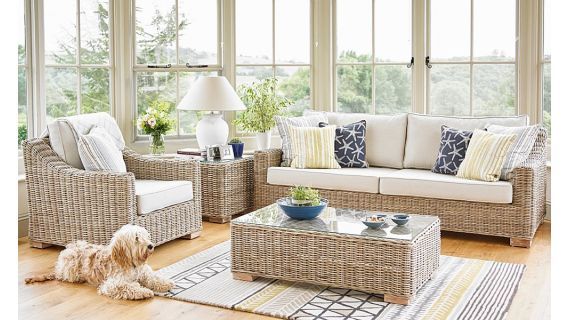 a living room with wicker furniture and large windows