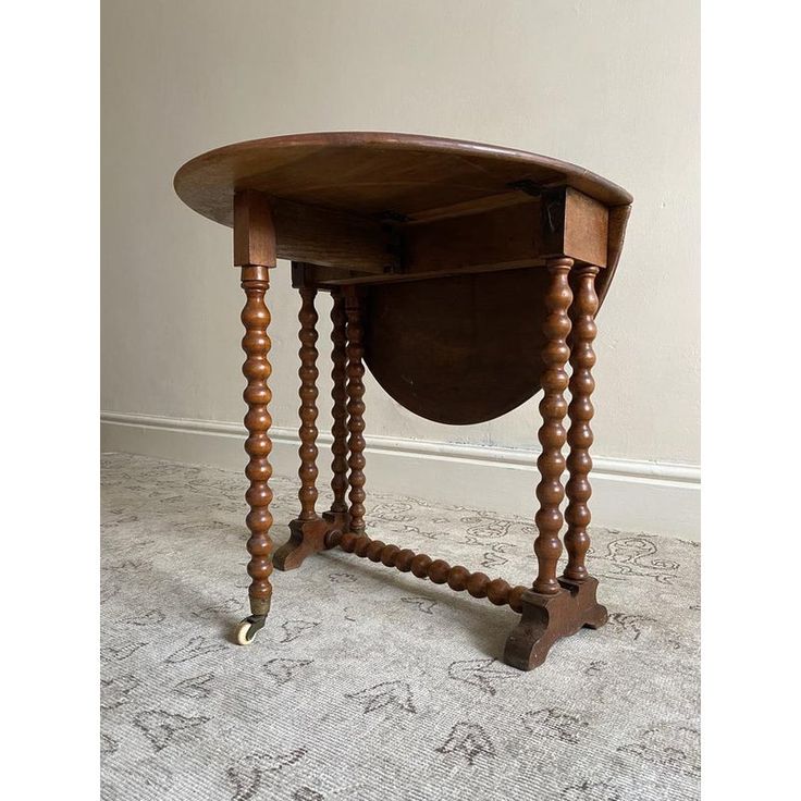 an old wooden table with two legs and a circular shaped top, on carpeted floor