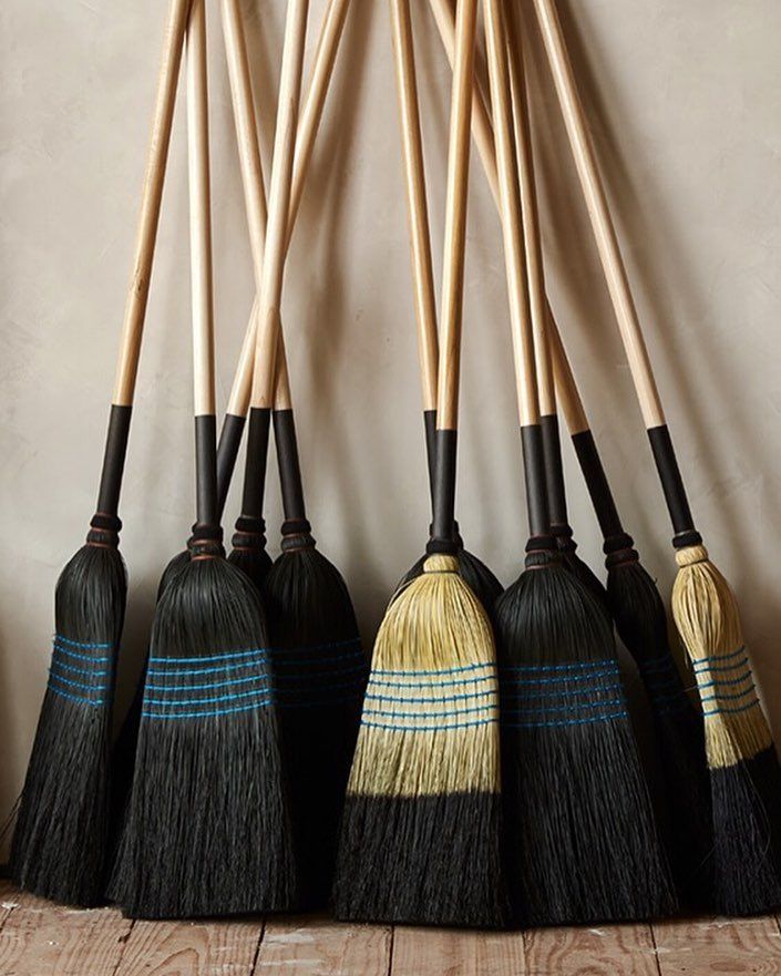 six brooms lined up against a wall