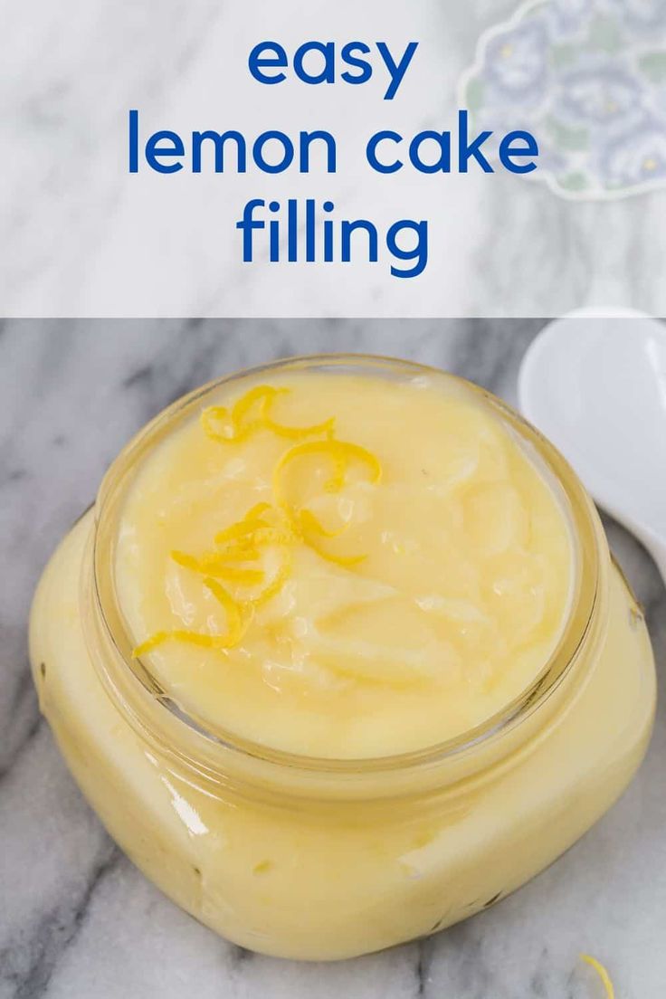 a glass jar filled with lemon cake filling on top of a marble counter next to a spoon