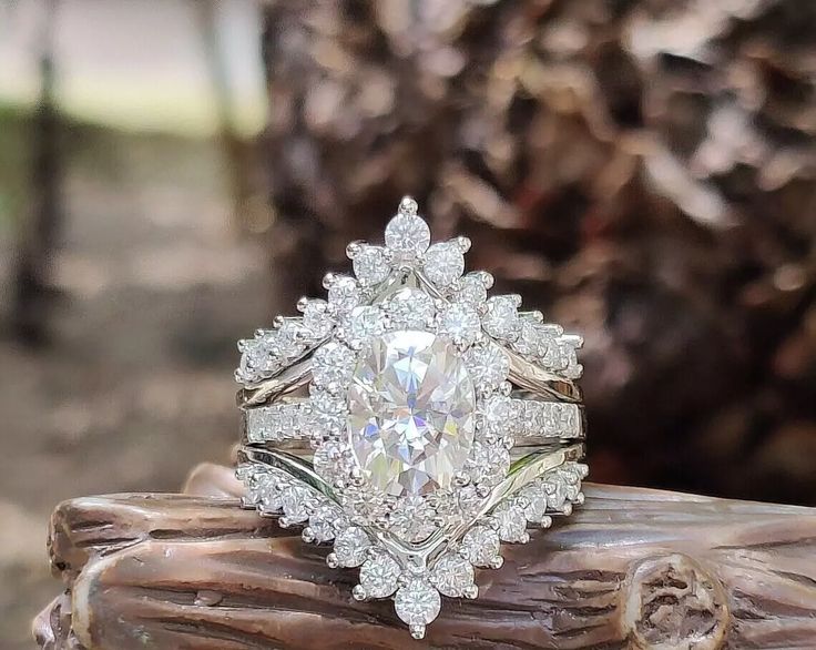 a diamond ring sitting on top of a piece of driftwood in front of a tree