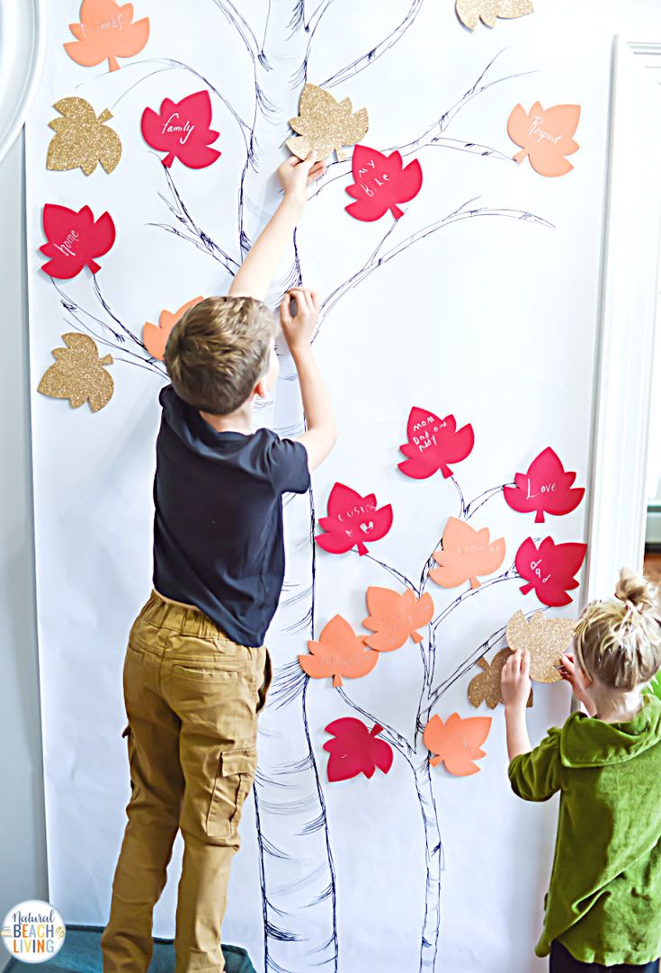 two young boys are painting a tree with hearts on the wall and one boy is holding a stick