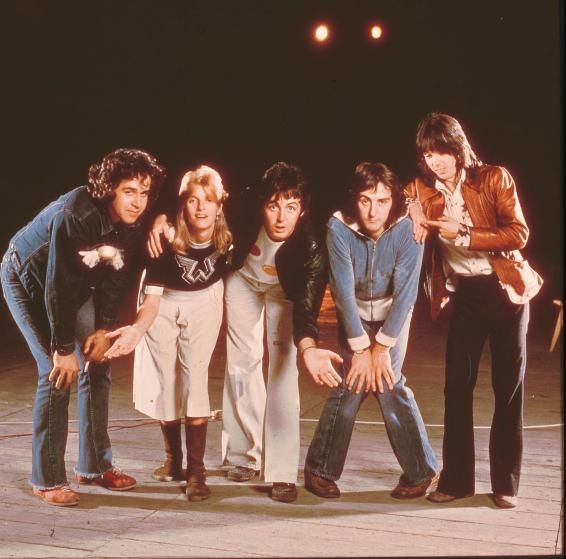 the rolling stones pose for a group photo in front of a black background with their arms around each other