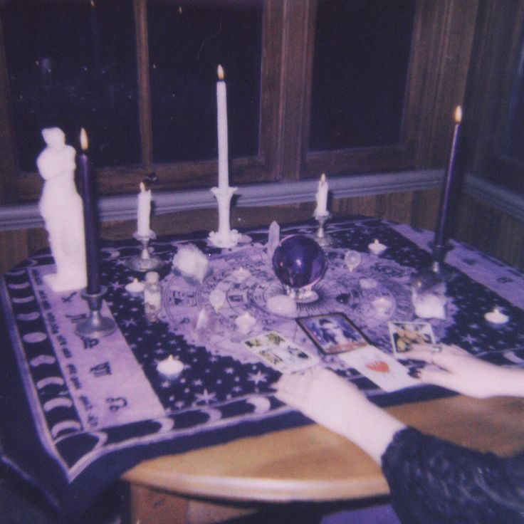 a person sitting at a table with candles and pictures on the table cloth in front of them