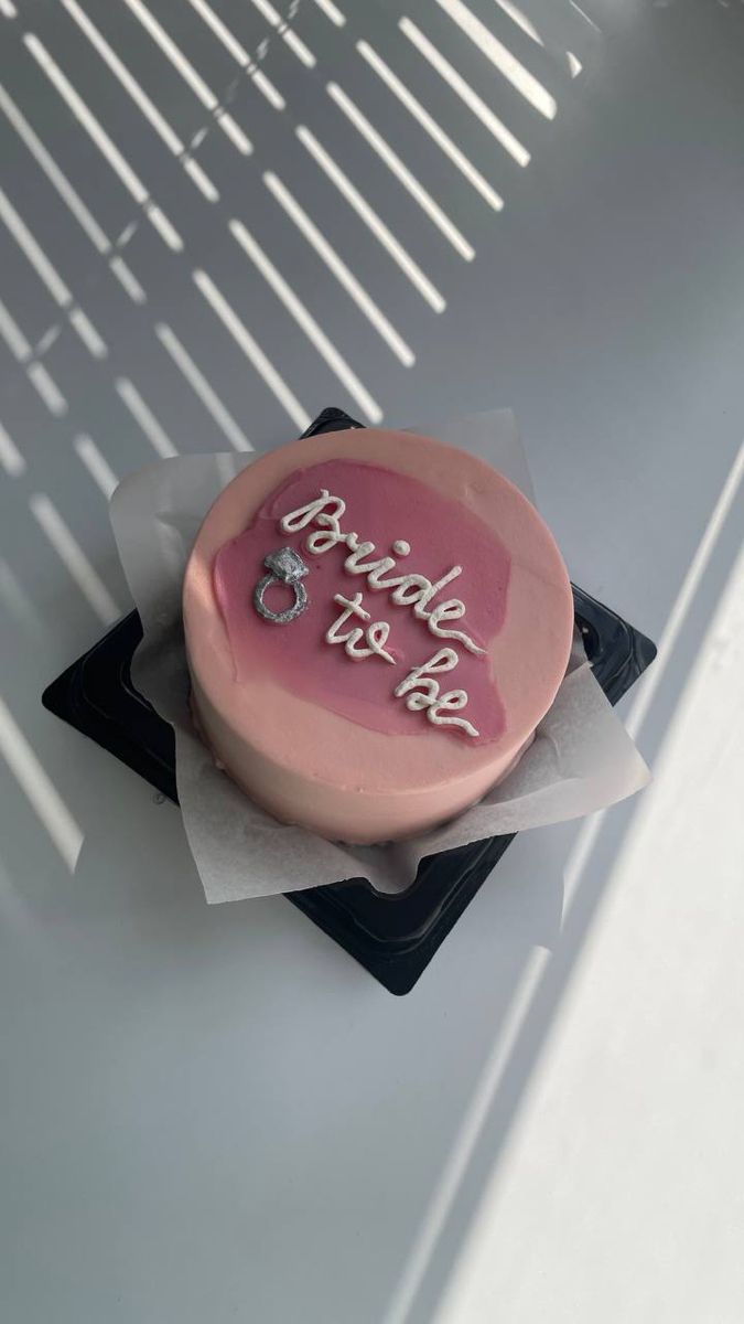 a pink birthday cake sitting on top of a table