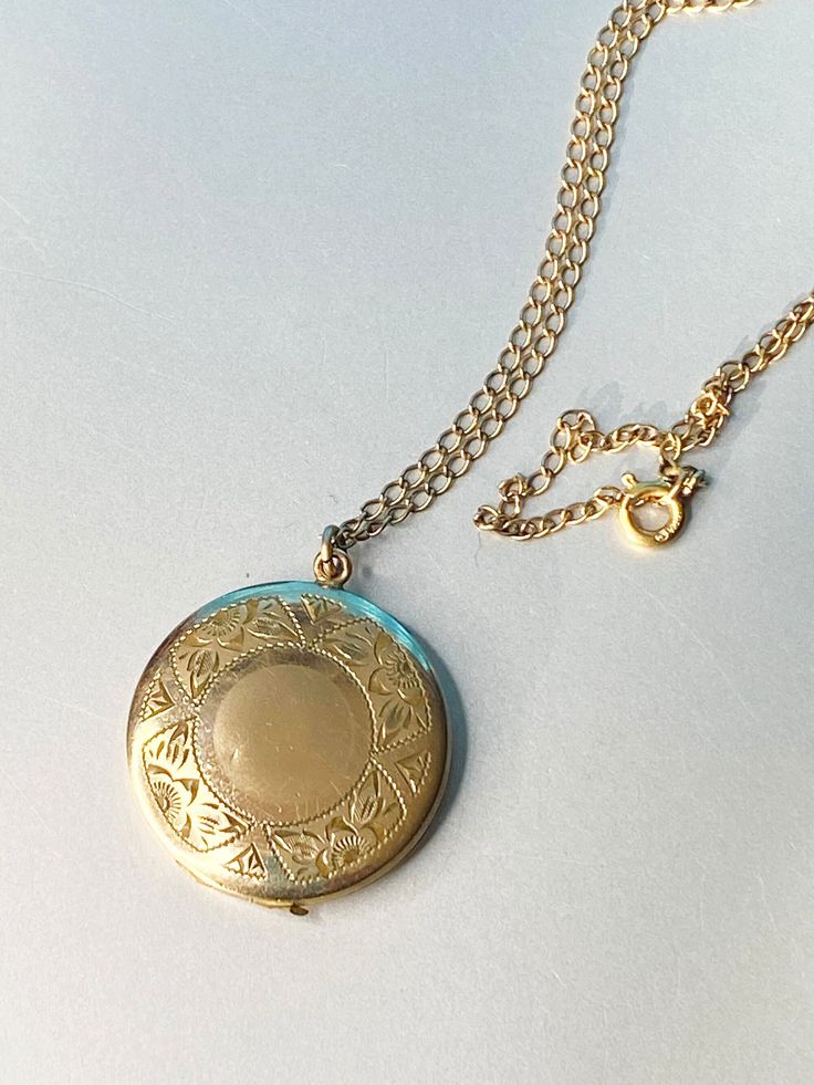 "Up for sale is vintage locket from the approximate 30-40's era with a beautiful engraved floral design on front. MARKINGS: The inside is marked 1 20 12kt GF and the initials MB in a cartouche.  The chain is marked  1/20 12 kt gf and a makers mark I cannot discern. I tried to find out who the maker was but had no luck. If one of you out there knows this maker, please contact  me so that I can make notes for my future listings and update this one. DESCRIPTION: This beautiful locket is 1\" in diameter. There is an engraved floral pattern that goes all the way around the front. There is a blank center where you could put your own initials or a special date. It locks on the top of the locked and a fingernail will open it. It has both the chucks on the inside and one side has the protective pho Antique Medallion Locket Necklace Stamped 14k, Antique Gold Locket Necklace Stamped 14k, Victorian Round Locket Necklace Stamped 14k, Vintage 14k Gold Locket Necklace, Vintage 14k Gold Locket Necklace Stamped 14k, Formal Yellow Gold Filigree Locket Necklace, Antique Gold Filigree Locket Necklace For Formal Occasions, Classic 14k Stamped Medallion Locket Necklace, Yellow Gold Round Filigree Locket Necklace