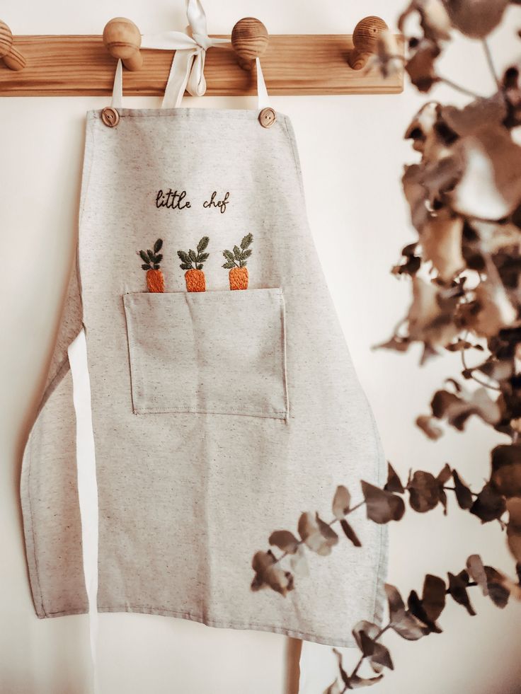 an apron hanging on a wall with carrots printed on the front and back pocket