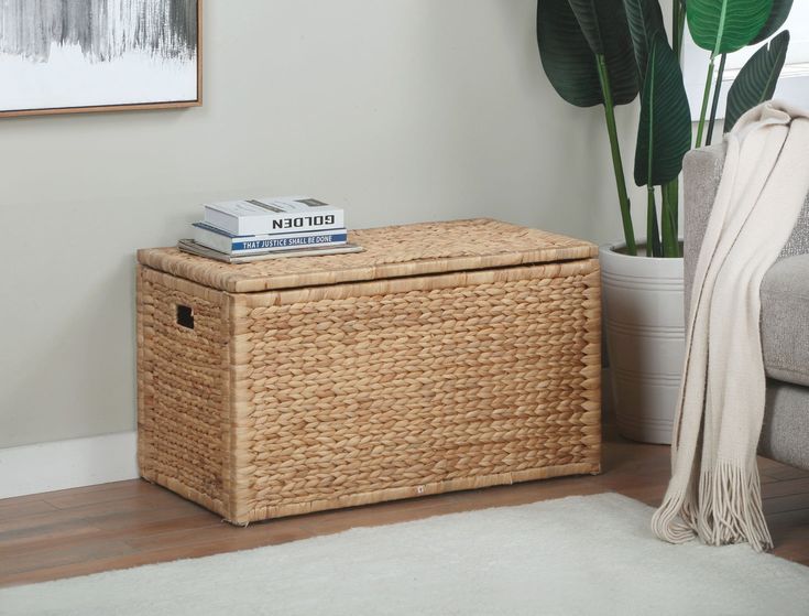 a wicker box with books on top sits next to a couch