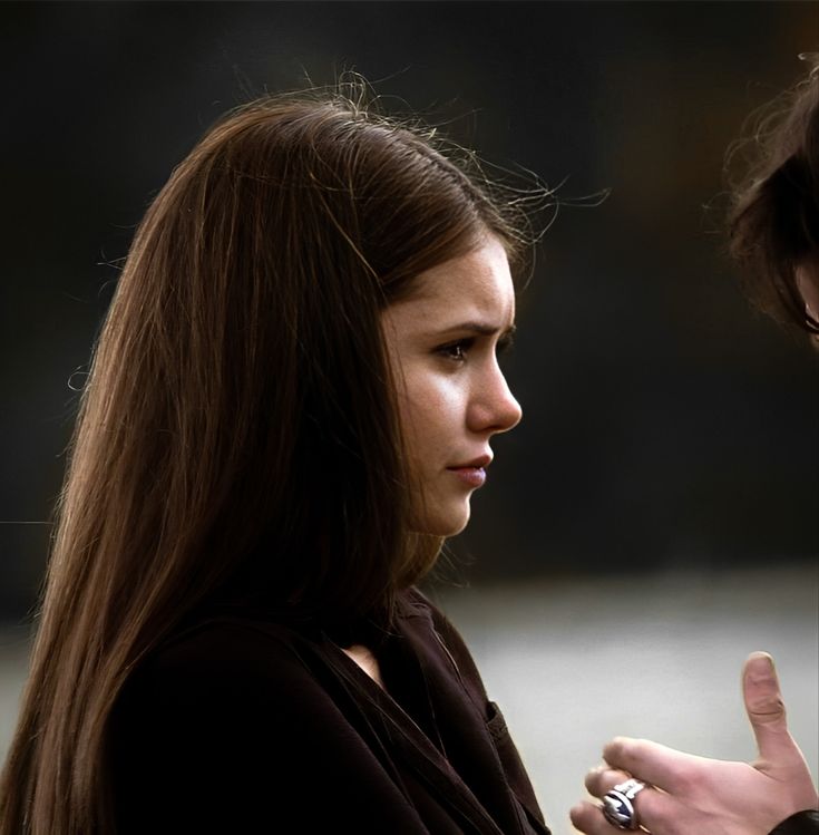 a woman with long hair standing next to a man