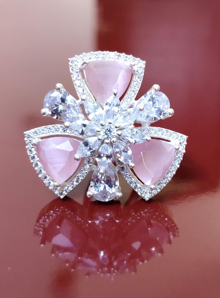 a pink and white diamond ring sitting on top of a table