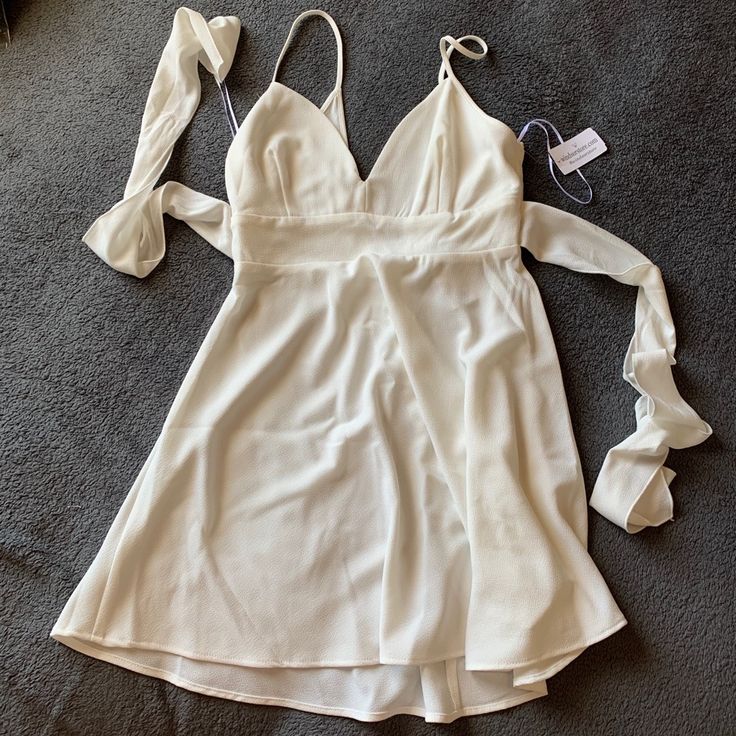 a white dress on the floor next to a pair of shoes and a hair clip