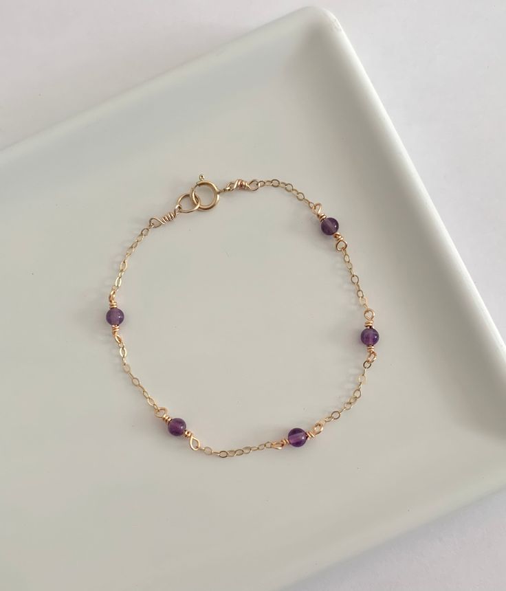 This dainty amethyst bracelet is handmade with genuine amethyst, and 14k gold filled and sterling silver metals. - Each bead measures 3mm. - Waterproof - Will not tarnish - Size up and wear as an anklet All of our jewelry is handmade with love in Nova Scotia, Canada. METALS Our jewelry is made using 925 sterling silver or 14k gold filled metals. Gold filled metals are made with a thick layer of gold to a brass core. Is is of higher quality than plated jewelry, and is a great alternative to pure Purple Jewelry Bracelet With Adjustable Chain, Purple Amethyst Charm Bracelet For Gift, Purple Amethyst Charm Bracelet Gift, Elegant Purple Birthstone Beaded Bracelets, Purple Wire Wrapped Bracelets As Gift, Dainty Handmade Purple Bracelets, Elegant Adjustable Purple Chain Bracelet, Dainty Lavender Amethyst Jewelry, Purple Amethyst Birthstone Bracelet