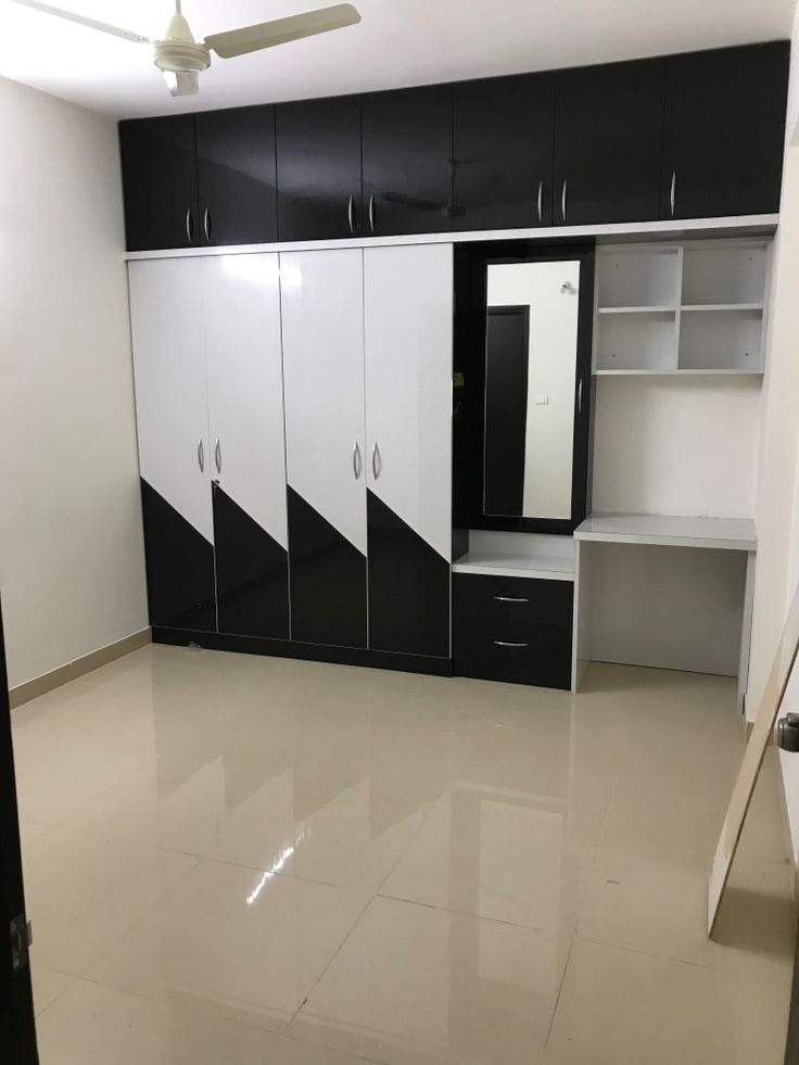 an empty room with black and white cupboards, shelves, and a ceiling fan