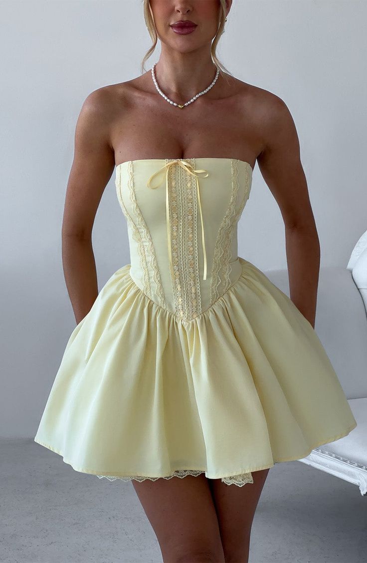 Fall in love with the Evie dress, a flirty mini with a super full skirt made with tulle for extra volume. This strapless style has a boned bodice for an extra snatched look, complete with ribbon to the bust and lace up back. Dress her up with effortless waves, pointed heels and metallic jewellery.



Colour: Lemon.

Non-stretch cotton blend fabric.

Fully lined.

Full skirt with tulle and gathered detail at waist.

Boned bodice with v-shape hem.

Strapless.

Ribbon tie at bust.

Lace trim detailing.

Lace up back.

Invisible zipper fastening.

Mini length.

Model is an XS and is wearing an XS.

 Size: XS, S, M, L, XL, XXL 21 Birthday Outfit Ideas, Short Birthday Dress, 21st Birthday Dress, Homecoming Dresses Satin, Vestidos Color Vino, Strapless Homecoming Dresses, Lace Up Back Dress, Dinner Dresses, Dresses Satin