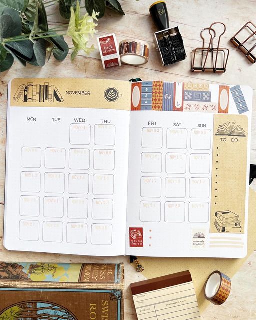 an open planner sitting on top of a table next to some books and other items