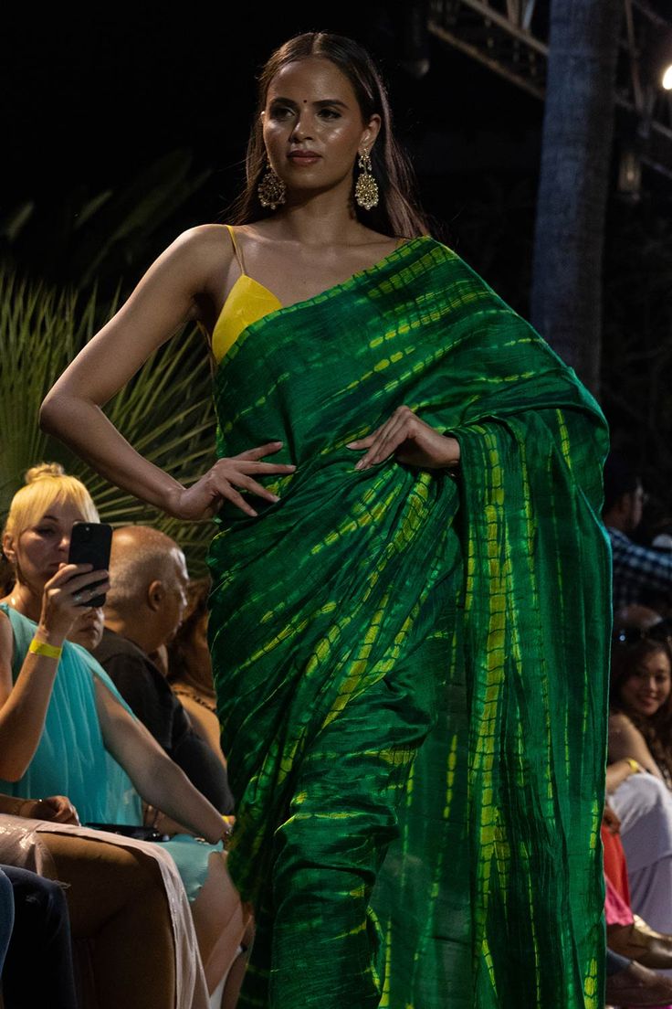 Upgrade your ethnic elegance with our Gia Green & Yellow Tie Dye Georgette Silk One Minute Saree. Crafted from luxurious raw silk, this stunning saree features a mesmerizing green-yellow tie-dye pattern. The pallu is adorned with vibrant yellow tassels, while the matching blouse comes with delicate spaghetti straps in yellow raw silk, adding a touch of sophistication to your traditional attire. Suitable for a summer night out, wedding party, pooja or any other function! About this Product Saree: Transitional Green Pre-draped Saree With Self Design, Green Chanderi Pre-draped Saree For Festivals, Green Chanderi Pre-draped Saree For Puja, Green Handloom Chanderi Pre-draped Saree, Green Slub Silk Pre-draped Saree For Diwali, Green Tussar Silk Pre-draped Saree With Dupatta, Designer Green Blouse Piece For Festivals, Traditional Green Slub Silk Pre-draped Saree, Green Raw Silk Blouse Piece With Cutdana