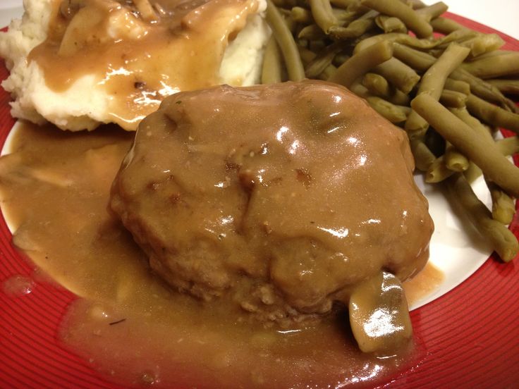 a red plate topped with mashed potatoes covered in gravy and green beans