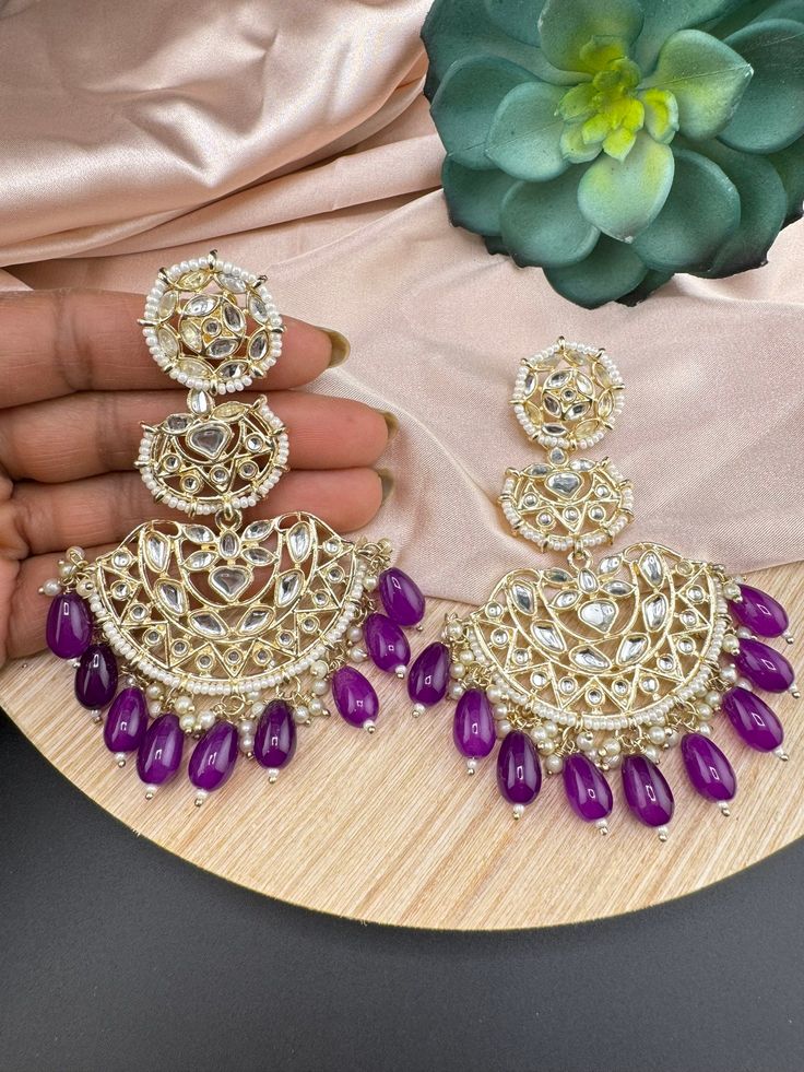 This a beautiful and Gorgeous Big gold and Kundan Big Punjabi Chandbali Oversized earring with stones and pearls detailed work. It is more pretty in person than seen in photos. This is so beautiful to look at and a perfect one for Indian weddings.  Color : Purple, Green, gold, white length : 4 inch width : 2.5 inch Each earring Weight : 29.5 grams Material : Brass , stones, Pearls Beautiful High Quality, premium jewelry. Free US standard shipping. Hand crafted in India with the finest design of Luxury Meenakari Chandelier Earrings For Wedding, Luxury Meenakari Bridal Earrings, Luxury Meenakari Bridal Drop Earrings, Luxury Meenakari Bridal Earrings For Reception, Luxury Bollywood Bridal Earrings With Meenakari, Luxury Traditional Meenakari Bridal Earrings, Luxury Bridal Earrings With Stone Work For Festivals, Luxury Meenakari Bridal Earrings For Celebrations, Luxury Bollywood Earrings With Stone Work