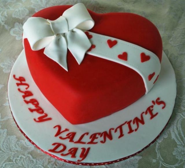 a red and white heart shaped cake sitting on top of a table