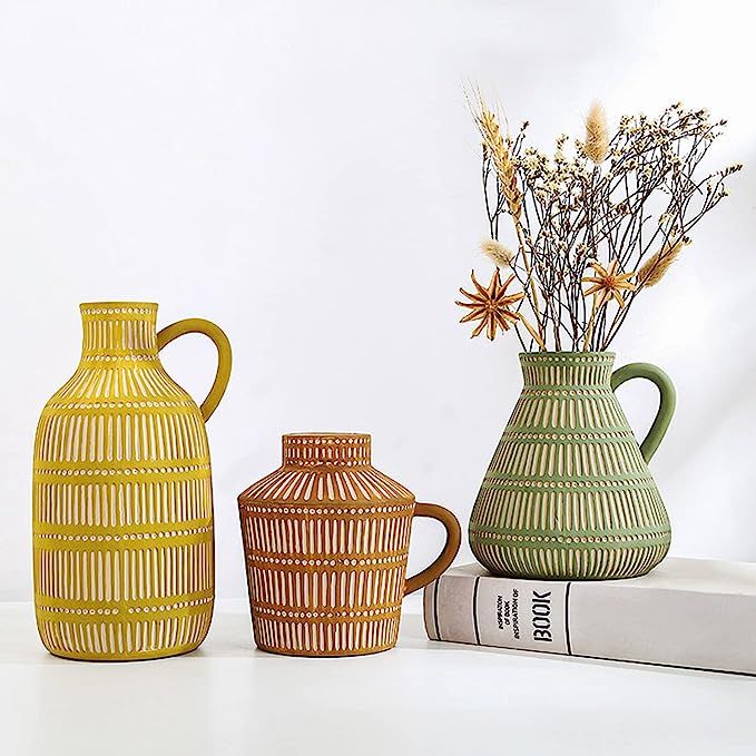 three vases sitting next to each other on top of a book and some flowers