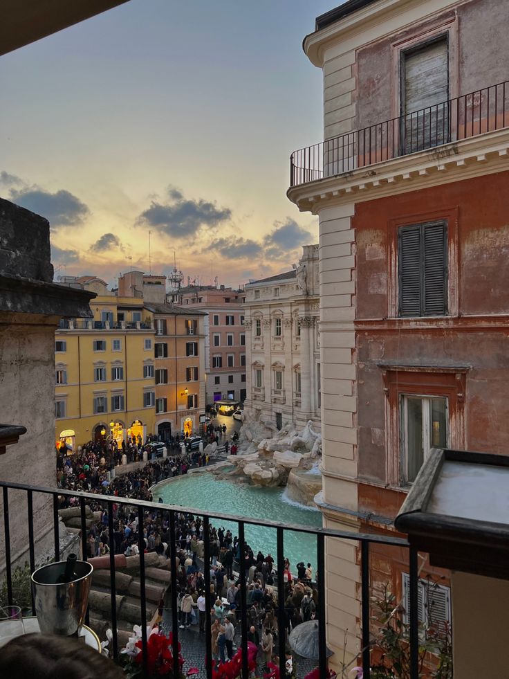 people are gathered at the top of a balcony overlooking a cityscape and fountain