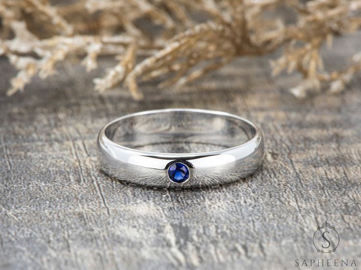 a silver ring with a blue stone in the middle on top of a wooden table