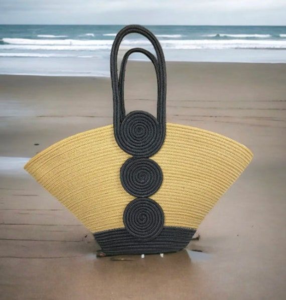 a black and yellow basket sitting on top of a sandy beach