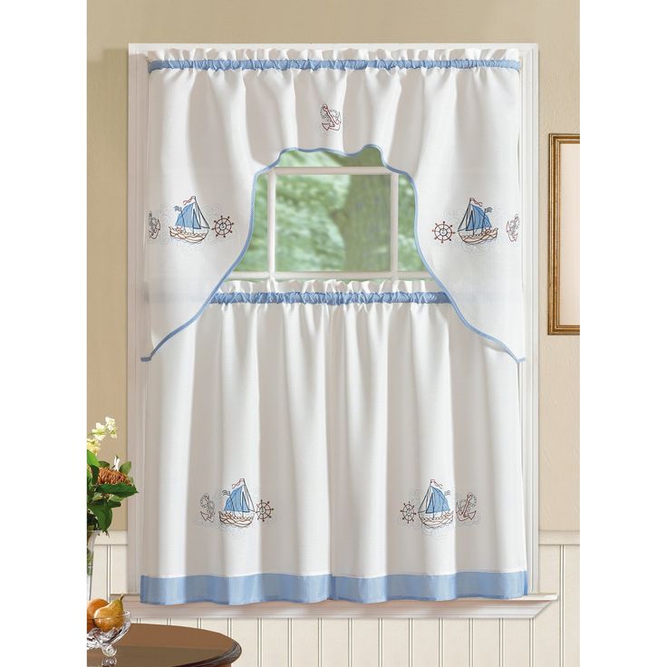 a kitchen window curtain with blue trim and sailboats on the valance, in front of a dining room table