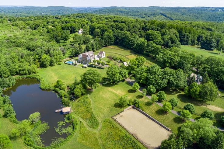 an aerial view of a large estate surrounded by trees and water in the middle of a wooded area