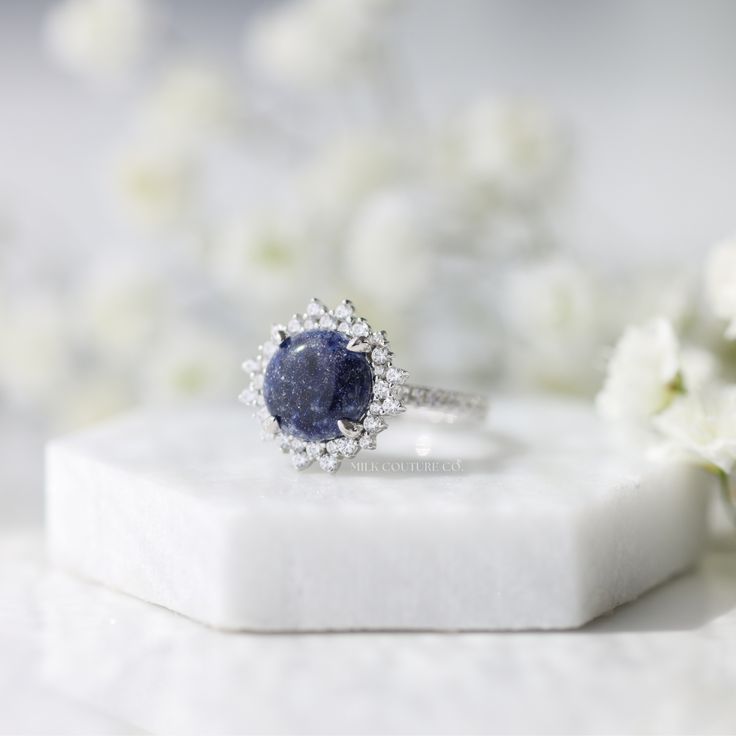 The Stella ring is a work of art, intricately designed to resemble a star in the night sky. The round center keepsake stone is the centerpiece of the design, and it sits nestled in the center of the ring, surrounded by a halo of smaller stones that accentuate its beauty. Estelle means star in Italian, and this ring is named in honor of my late grandma Estelle. She was a woman who truly shined like a star, with the most unforgettable smile and laugh! Luxury Cluster Sapphire Ring With Center Stone, Luxury Round Cut Gemstones With Center Stone, Luxury Round Cut Center Stone Gemstones, Luxury Sapphire Gemstone Cluster Ring, Luxury Sapphire Cluster Ring With Gemstones, Luxury Cluster Ring With Sapphire In Round Cut, Luxury Sapphire Cluster Ring With Round Cut, Celestial Style Round Cut Diamond Jewelry, Luxury Halo Ring With Round Stone