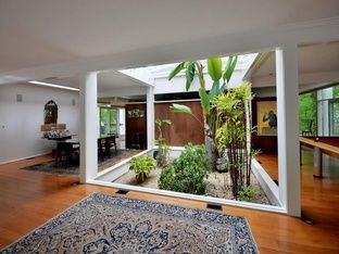 the interior of a house with wood floors and plants in the center, as well as an area rug on the floor