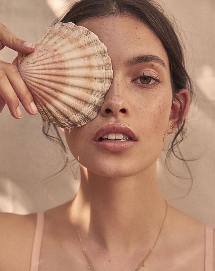 a woman holding a seashell up to her face