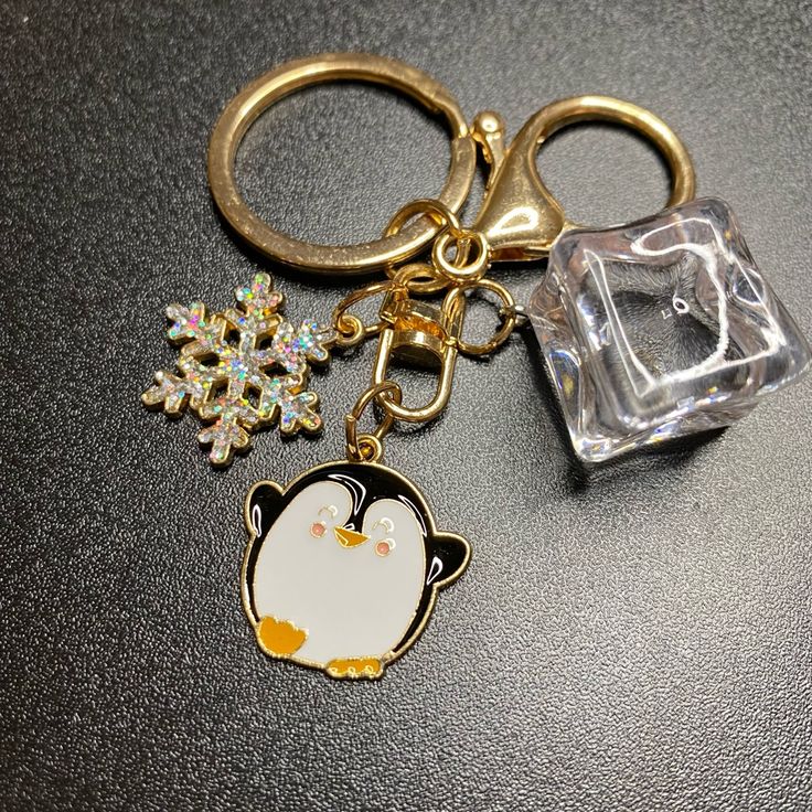 a key chain with a penguin and snowflake on it next to a glass block