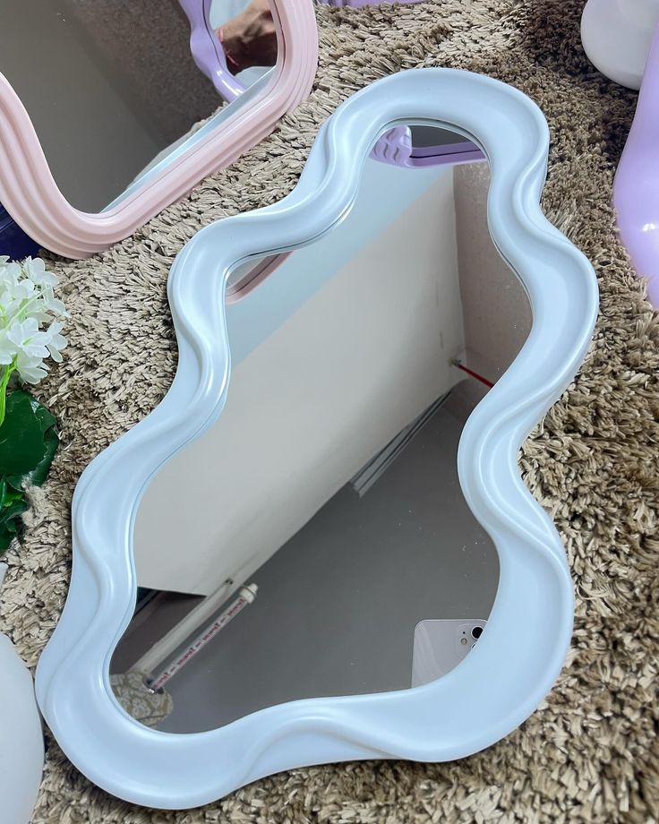 a white vanity mirror sitting on top of a counter next to vases and flowers