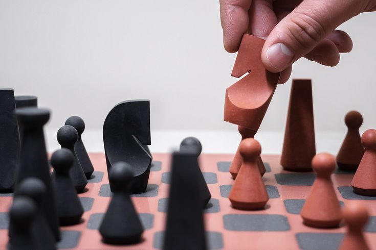 a person is playing chess on a checkered board with pieces in the foreground