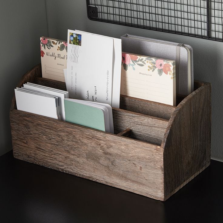 a wooden desk organizer with note cards and envelopes in it on a black table