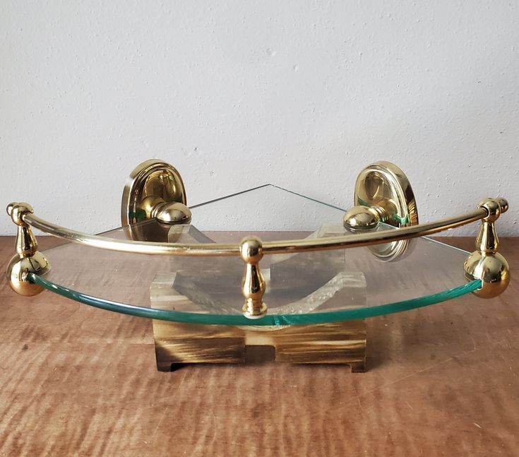 a glass shelf with brass fittings on the bottom and two metal balls attached to it