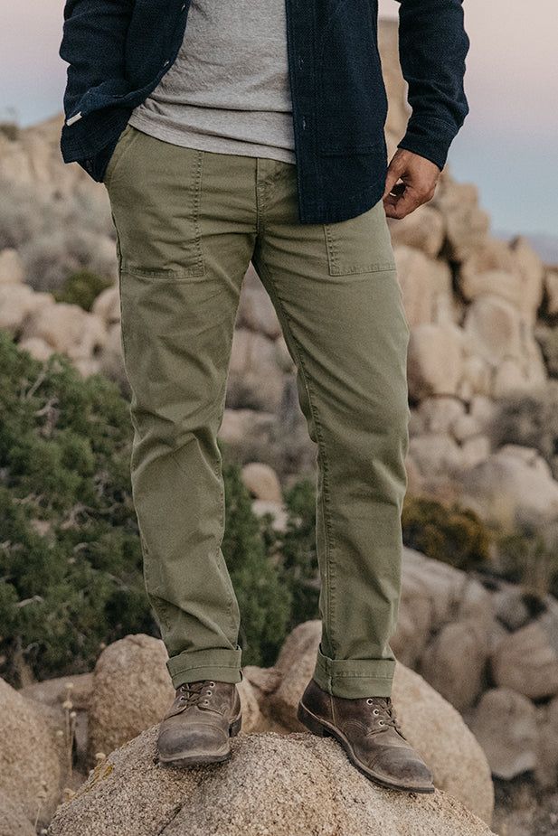 Introducing our Fatigue Pants, a modern interpretation of the vintage OG-107 military fatigue pants. Inspired by the demanding tasks of "Fatigue Duty" assigned to soldiers during non-combat activities, these pants combine functionality with contemporary style. Crafted with a modern straight cut, they offer a more slim and fitted silhouette compared to their vintage counterparts. Made from a stretch twill Oxford fabric that has undergone garment/pigment dyeing, these pants exude a vintage broken-in look and feel. Completing the design are chocolate military buttons adorning the waistband and back pockets. Fall in with a perfect blend of rugged style and modern comfort with our Fatigue Pants.Available in three colors Moss, Whiskey, and Cobalt. • Straight Fit • Made in USA• 98%COTTON 2%POLYUR Mens Dress Attire, Green Pants Men, Green Pants Outfit, Fatigue Pants, Concept Clothing, Rugged Style, Belted Jacket, Oxford Fabric, Paige Denim