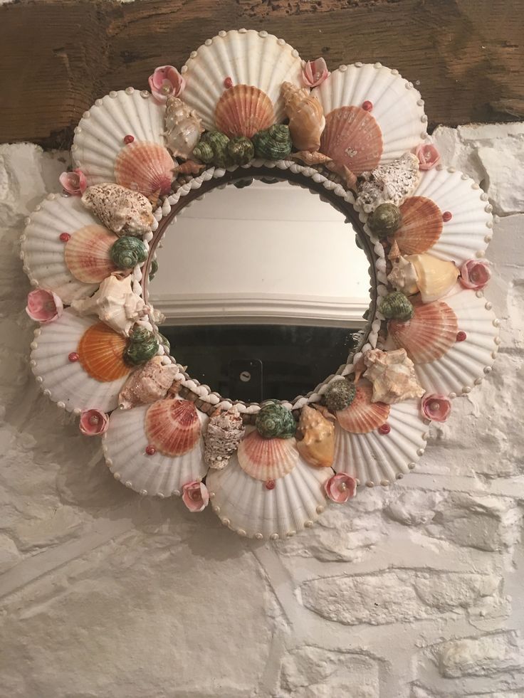 seashells and shells are arranged around a mirror on a stone wall in front of a window