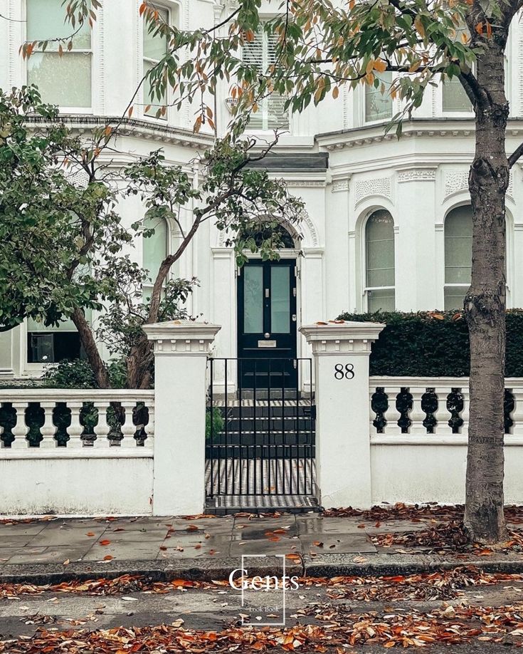 a white house with a black door and fence