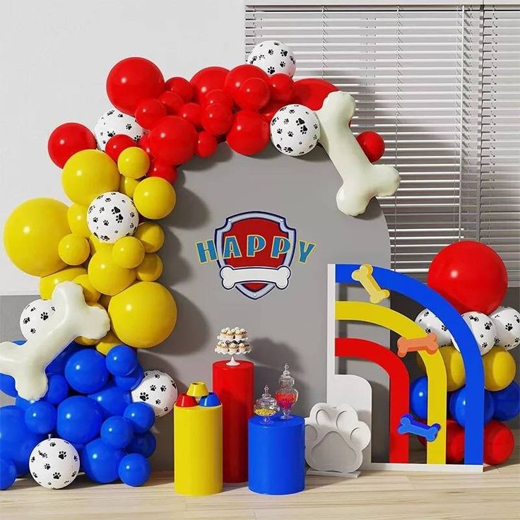 balloons and decorations are displayed in front of a party arch for a child's birthday