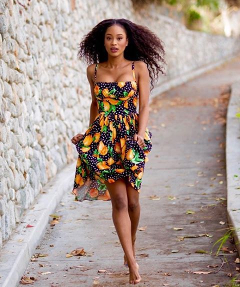 a woman walking down a sidewalk next to a stone wall