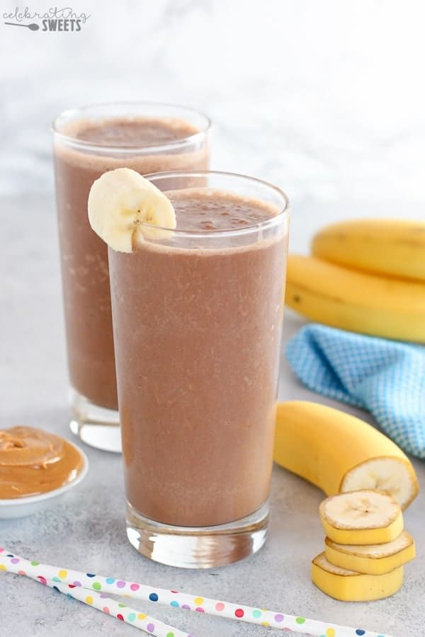 two glasses filled with chocolate peanut butter banana smoothie on top of a table next to bananas